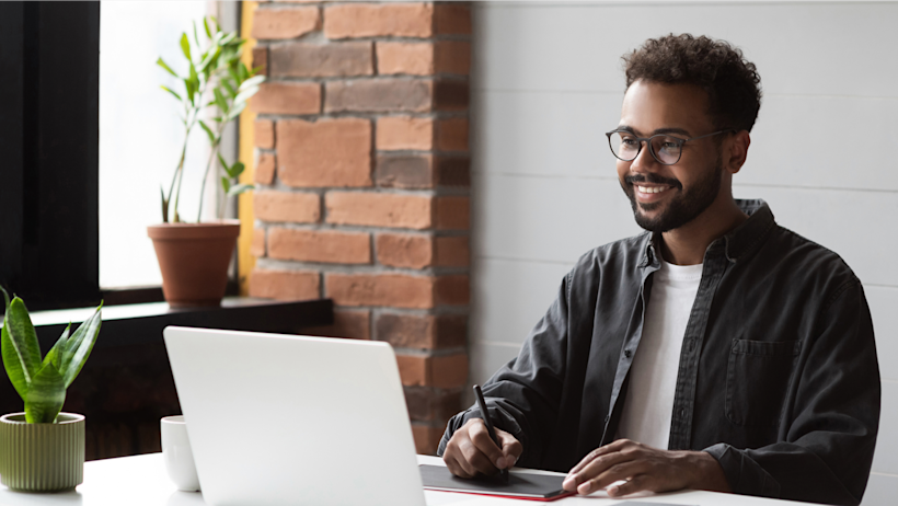 A person smiling while working on their laptop.